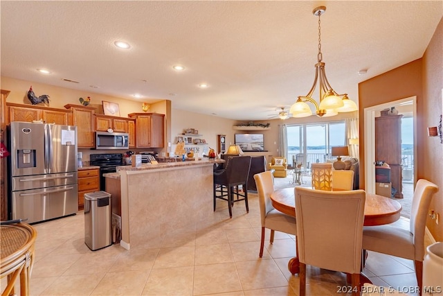 dining room featuring ceiling fan with notable chandelier, light tile patterned floors, and a textured ceiling