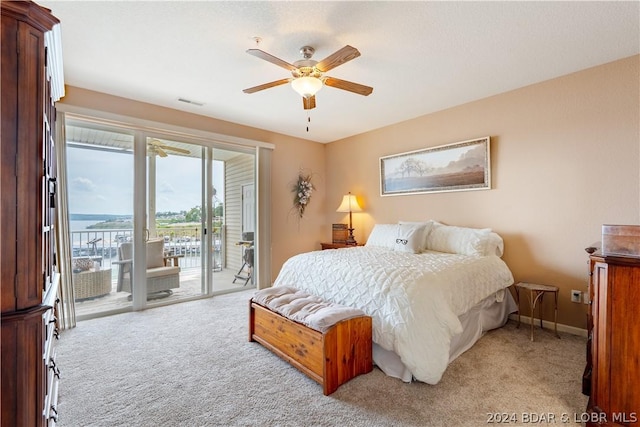 bedroom with a water view, access to exterior, light carpet, and ceiling fan