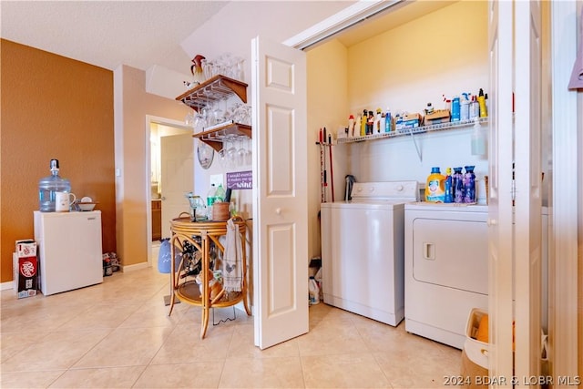 clothes washing area with washing machine and dryer and light tile patterned floors