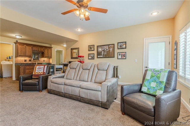 living room with washer / dryer, ceiling fan, and light carpet