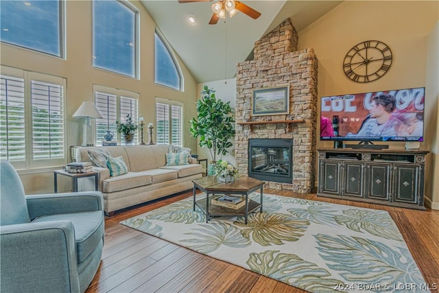 living room featuring high vaulted ceiling, a fireplace, ceiling fan, and hardwood / wood-style flooring