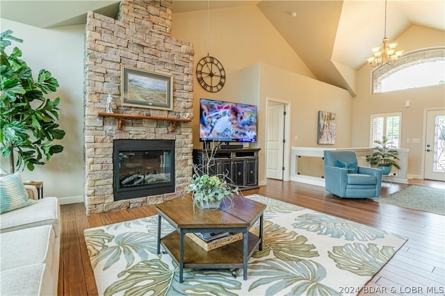 living room with high vaulted ceiling, a fireplace, hardwood / wood-style floors, and an inviting chandelier