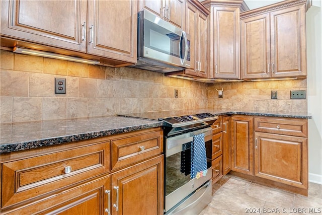 kitchen featuring dark stone counters, appliances with stainless steel finishes, light tile patterned floors, and tasteful backsplash