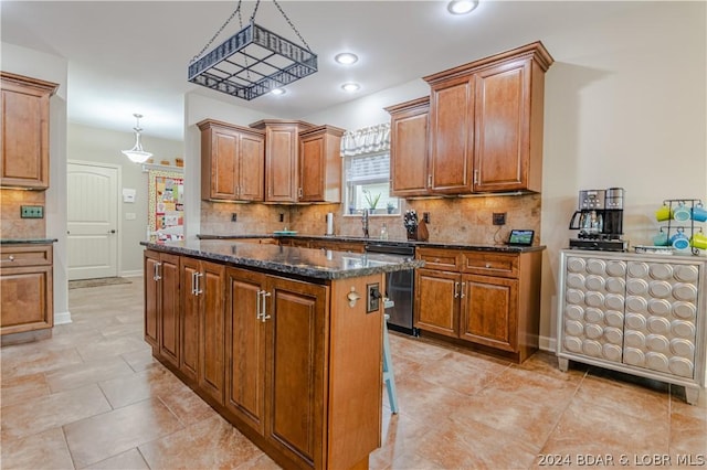 kitchen featuring a center island, dishwasher, dark stone countertops, tasteful backsplash, and pendant lighting