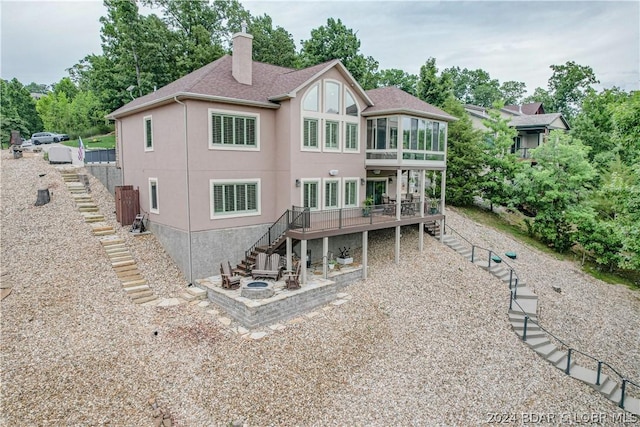 rear view of property with a deck, an outdoor fire pit, and a sunroom