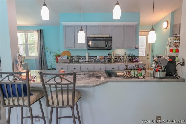 kitchen with decorative light fixtures, white fridge, and a kitchen breakfast bar