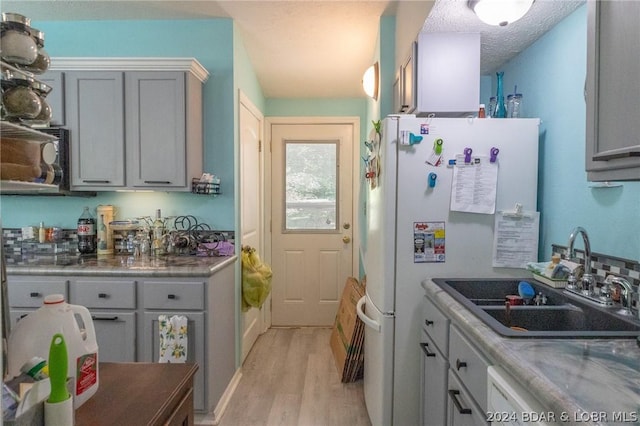 kitchen with sink, a textured ceiling, light hardwood / wood-style floors, and gray cabinetry