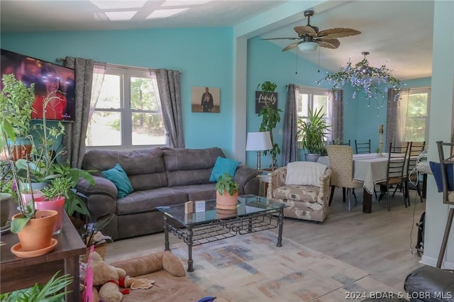 living room featuring a healthy amount of sunlight, ceiling fan, light wood-type flooring, and vaulted ceiling with beams