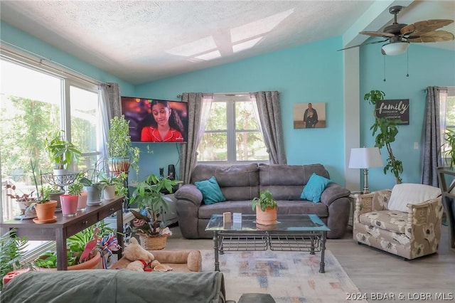 living room featuring ceiling fan, lofted ceiling, plenty of natural light, and a textured ceiling