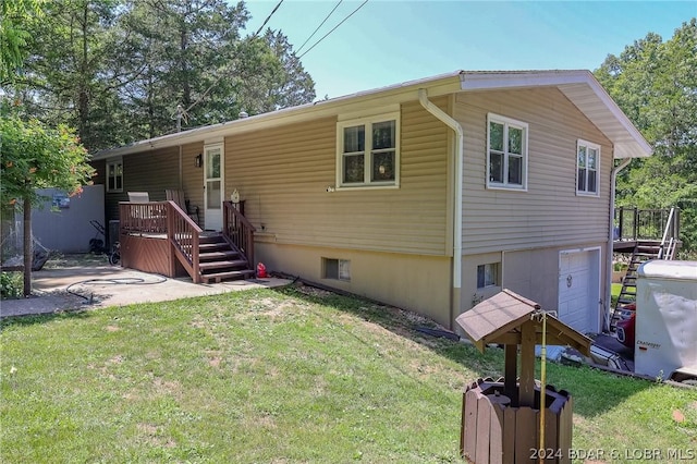 rear view of property with a lawn, a garage, and a wooden deck