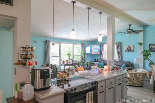 kitchen featuring black range with electric stovetop, ceiling fan, decorative light fixtures, and lofted ceiling