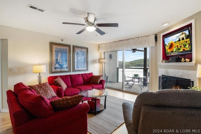 living room featuring ceiling fan, hardwood / wood-style floors, and a fireplace