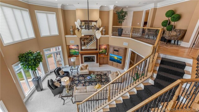 living room with crown molding, a towering ceiling, and carpet flooring