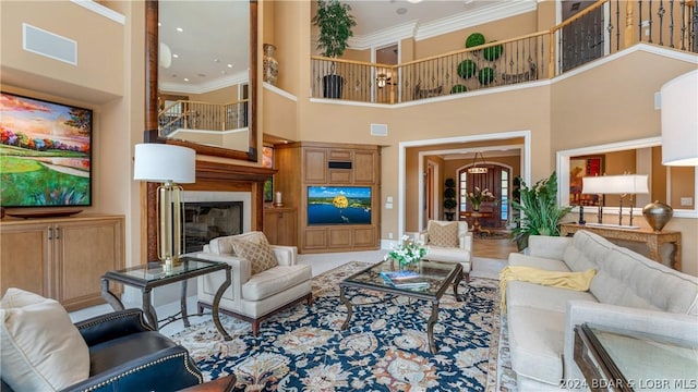 living room featuring a towering ceiling, an inviting chandelier, and ornamental molding