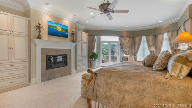 carpeted bedroom with ceiling fan, access to exterior, a tile fireplace, and crown molding