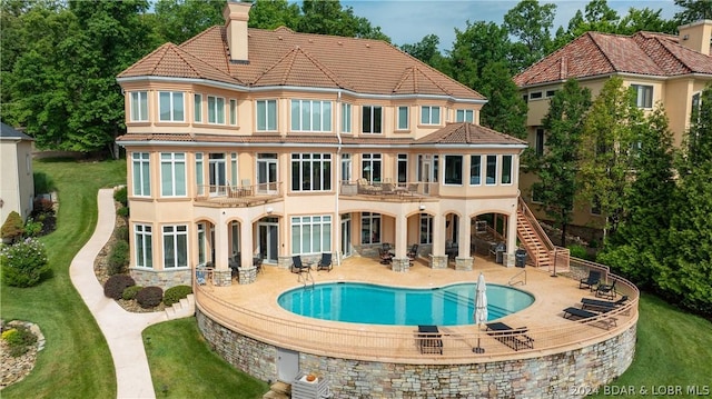 rear view of house with a balcony, a chimney, stairway, a tiled roof, and a patio area