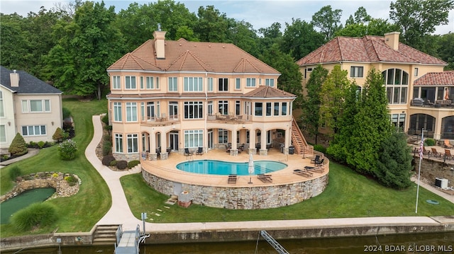 rear view of house with a lawn, a balcony, and a patio