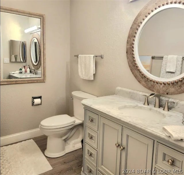 bathroom with toilet, wood-type flooring, and vanity