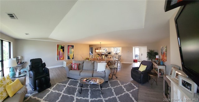 living room featuring lofted ceiling, hardwood / wood-style flooring, and an inviting chandelier