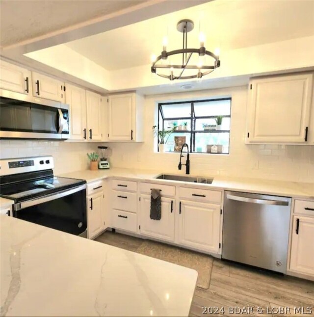 kitchen featuring appliances with stainless steel finishes, pendant lighting, and white cabinetry