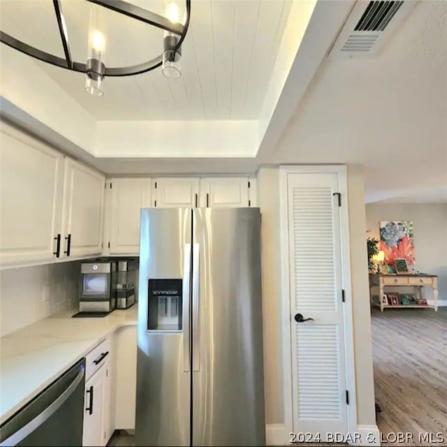 kitchen with stainless steel appliances, white cabinetry, hardwood / wood-style floors, and tasteful backsplash