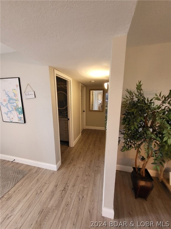 hall with light hardwood / wood-style floors and a textured ceiling