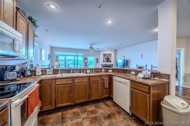 kitchen featuring sink, a textured ceiling, white appliances, ceiling fan, and kitchen peninsula