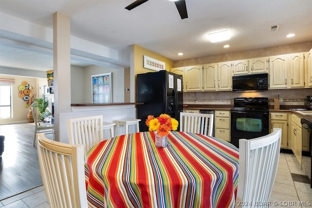 kitchen featuring backsplash, light tile patterned floors, black appliances, and a textured ceiling