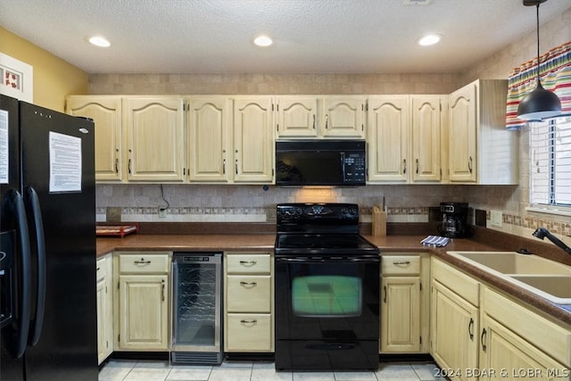 kitchen featuring sink, light tile patterned flooring, black appliances, and beverage cooler