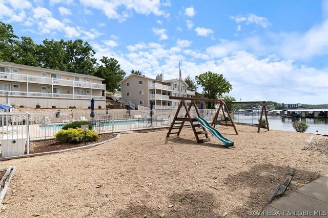 view of playground featuring a community pool and a water view