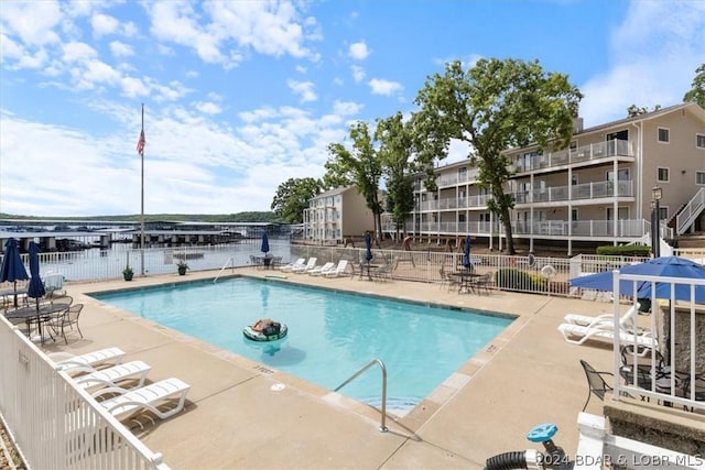 view of pool featuring a water view and a patio area