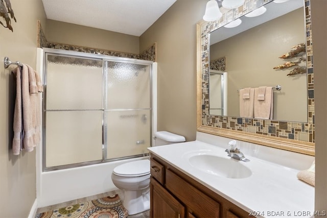 full bathroom featuring combined bath / shower with glass door, backsplash, toilet, and vanity