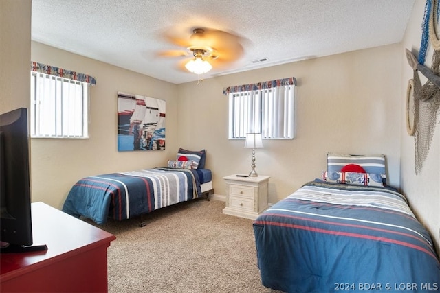 bedroom featuring a textured ceiling, multiple windows, light colored carpet, and ceiling fan