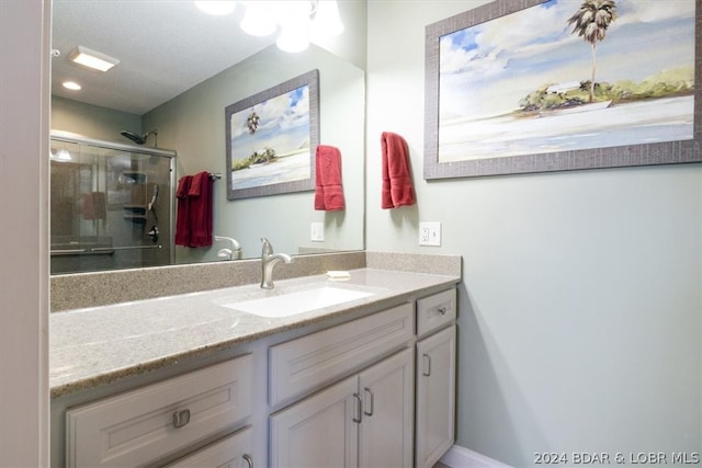 bathroom with a shower with shower door and vanity