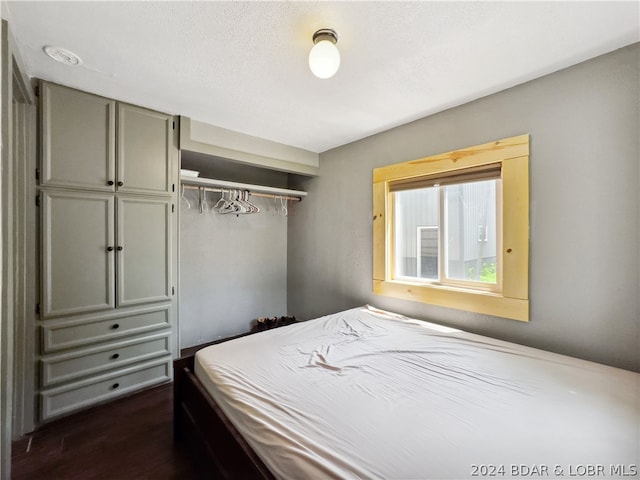 bedroom with dark hardwood / wood-style floors and a closet