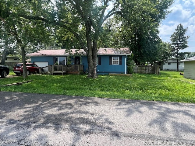 ranch-style home with a front yard, a garage, and a wooden deck