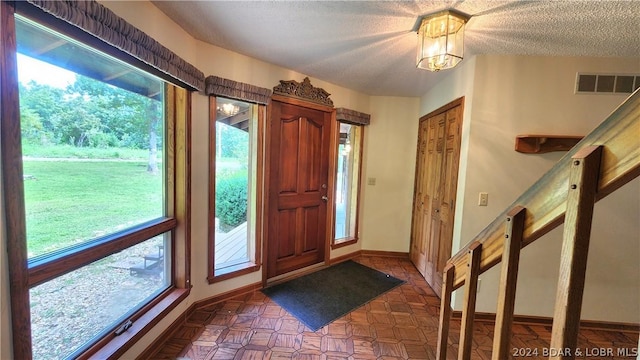 foyer entrance with an inviting chandelier and a textured ceiling