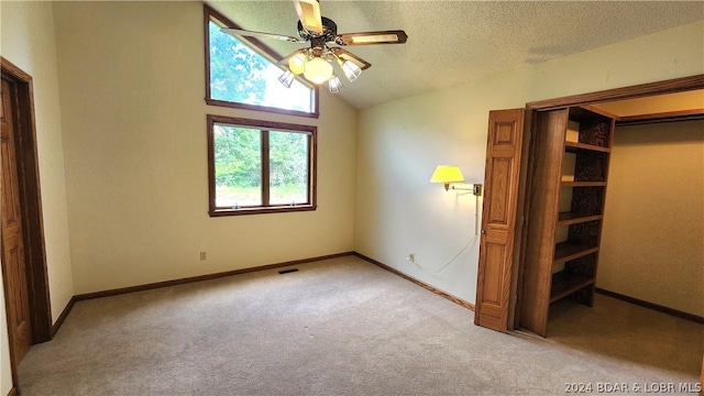 unfurnished bedroom featuring vaulted ceiling, light colored carpet, ceiling fan, and a textured ceiling