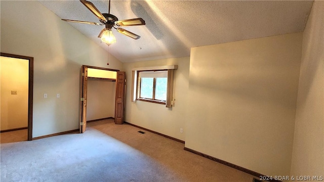 unfurnished bedroom featuring vaulted ceiling, ceiling fan, light carpet, a textured ceiling, and a closet