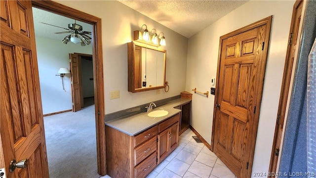 bathroom with vanity, ceiling fan, and a textured ceiling