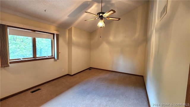 empty room with vaulted ceiling, light colored carpet, a textured ceiling, and ceiling fan