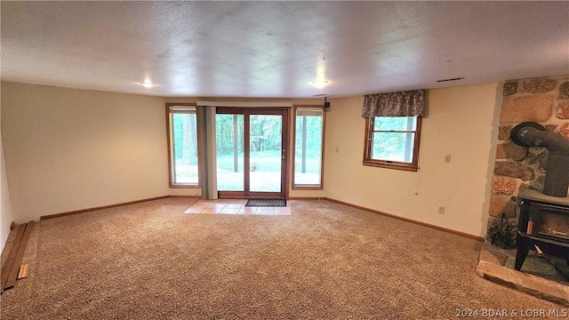 unfurnished living room featuring light colored carpet, a textured ceiling, and a baseboard heating unit