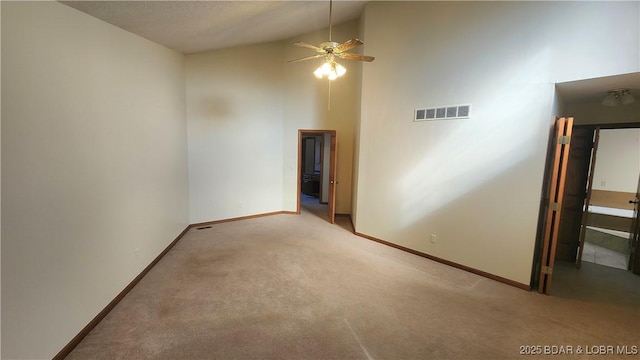 carpeted empty room with ceiling fan and high vaulted ceiling