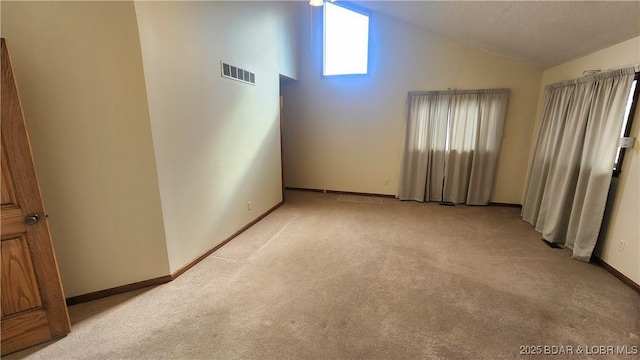 spare room with high vaulted ceiling and light colored carpet