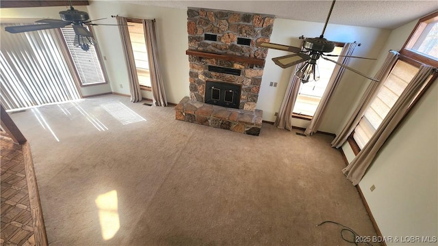 unfurnished living room featuring ceiling fan, light carpet, a textured ceiling, and a fireplace