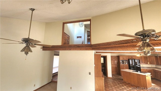 kitchen featuring black fridge, stainless steel microwave, ceiling fan, and kitchen peninsula