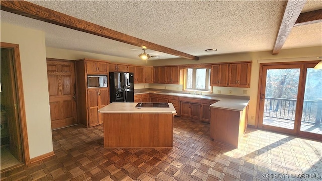 kitchen featuring sink, a center island, a textured ceiling, beamed ceiling, and black appliances