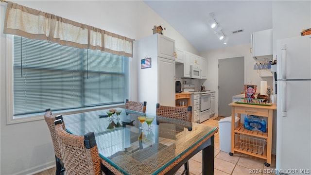 dining area featuring lofted ceiling and light tile patterned floors