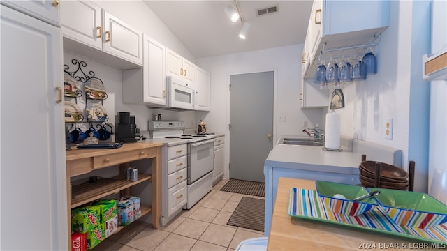 kitchen featuring white appliances, track lighting, white cabinets, sink, and light tile patterned floors