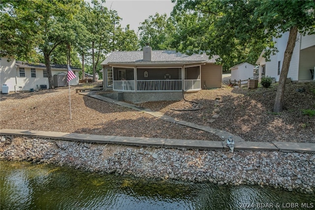 view of front of property featuring a water view and a storage shed